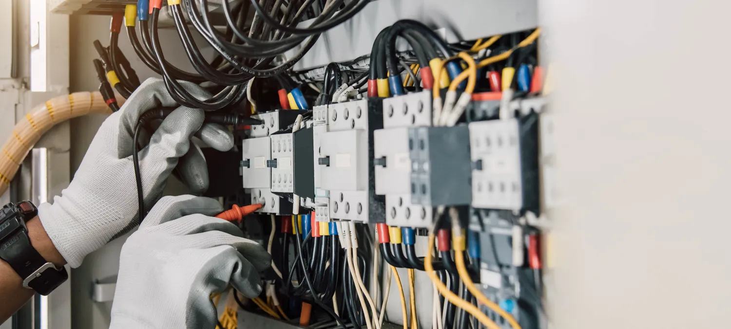 Pötschke Elektro - Elektrofachunternehmen - Ein Elektrotechniker prüft elektrische Anlagen und Leitungen an einem Relais-Schutzsystem.
